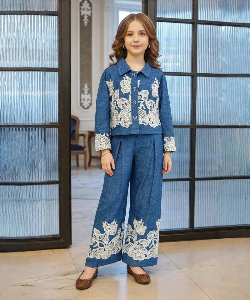 Person wearing a blue outfit with white floral embroidery in an indoor setting.