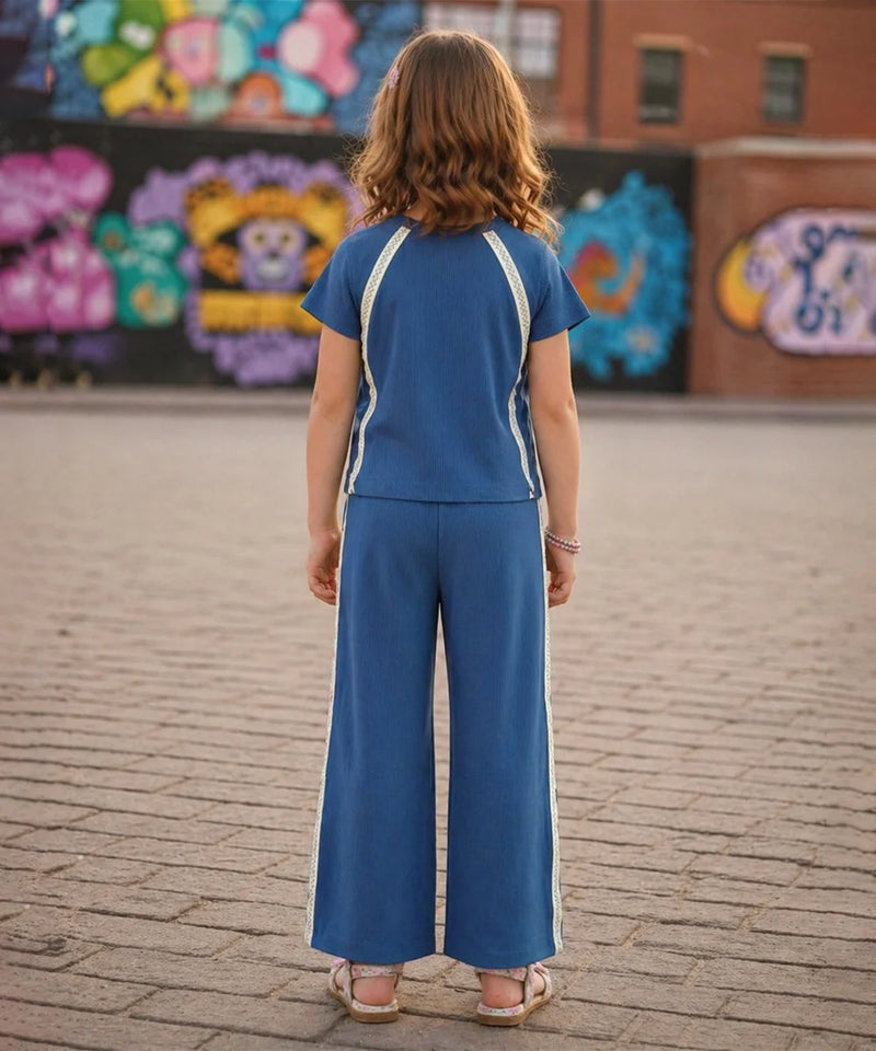 Person wearing a blue outfit with white stripes standing on a brick pavement in front of colorful murals.