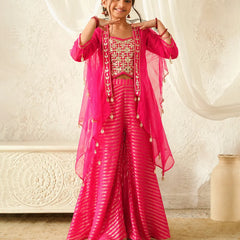 Woman in a pink traditional outfit with gold accents against a white curtain background