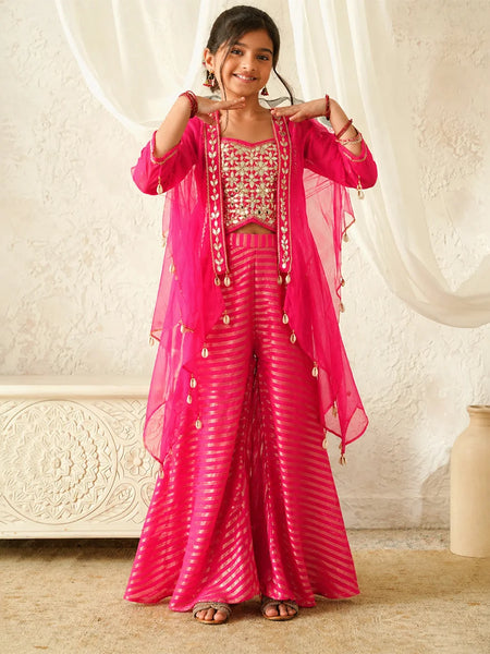 Woman in a pink traditional outfit with gold accents against a white curtain background