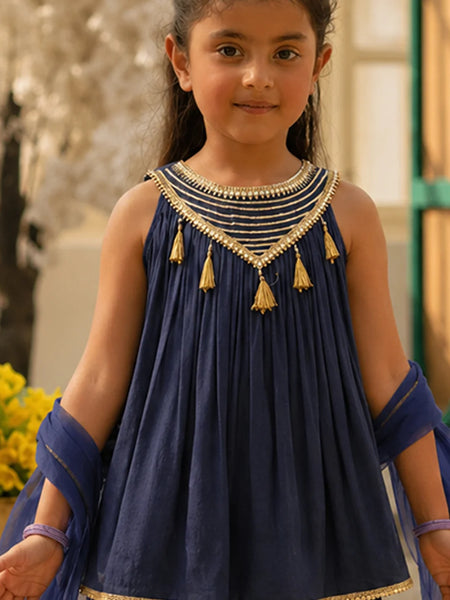 Young girl wearing a blue traditional outfit with gold details outdoors.
