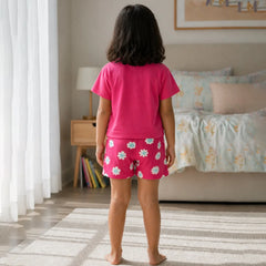 Child wearing pink pajamas with a floral pattern in a bedroom.