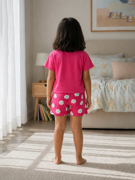 Child wearing pink pajamas with a floral pattern in a bedroom.