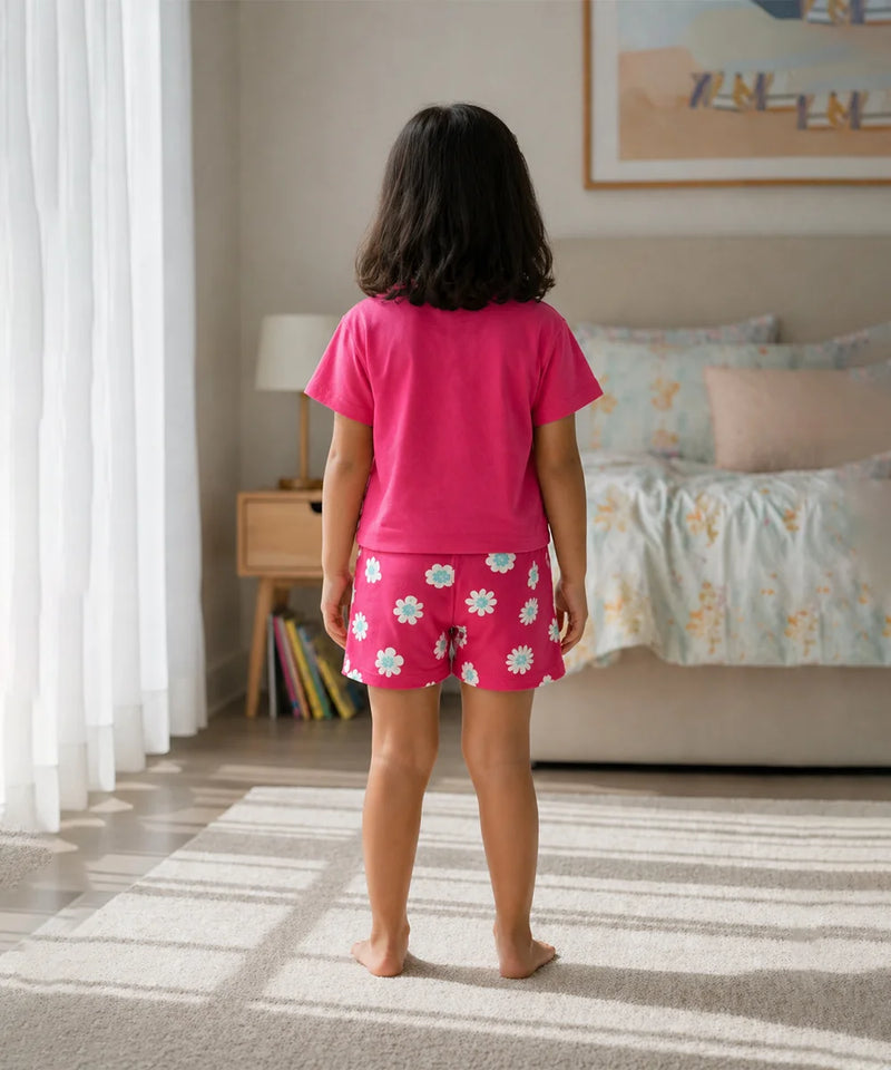 Child wearing pink pajamas with a floral pattern in a bedroom.