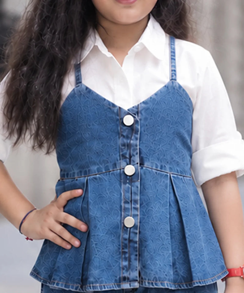 A child wearing a blue denim camisole-style vest with front buttons over a white collared shirt, shown from the shoulders to the hips against a softly blurred outdoor background.