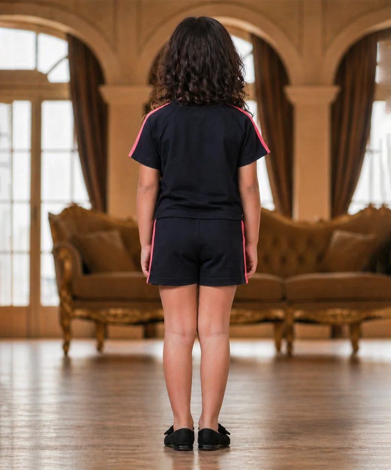 Person wearing a black outfit with pink accents in a room with brown furniture and large windows.