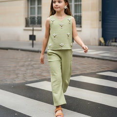 Young girl in a green outfit walking on a city street.
