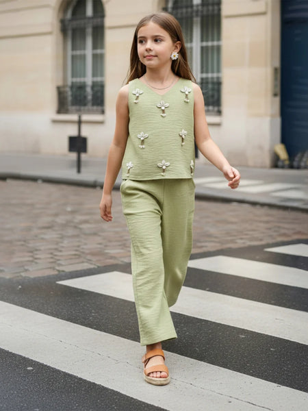Young girl in a green outfit walking on a city street.