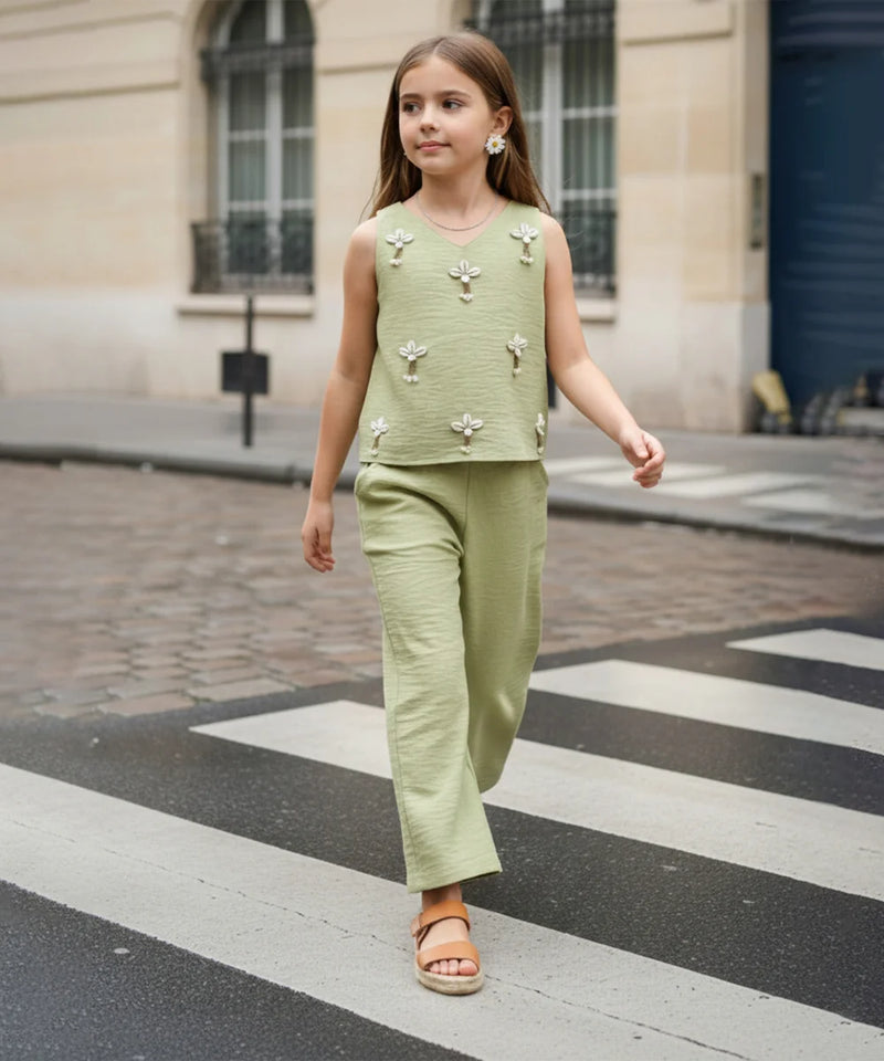 Young girl in a green outfit walking on a city street.