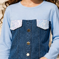 A close-up of a child wearing a light blue long-sleeve top with a dark blue denim-style front panel, sequined flap pockets, and gold-tone buttons.