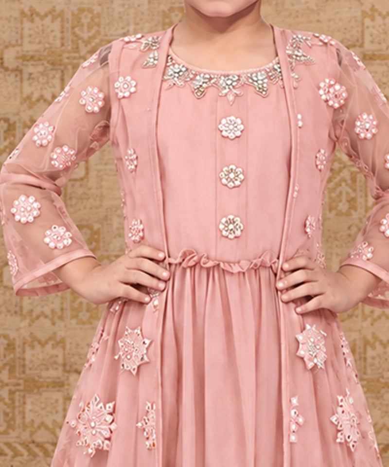 A pink traditional Indian dress with intricate floral embroidery and beadwork, shown on a model against a patterned beige background.