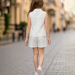 Young girl in a white outfit walking down a street with a blurred background