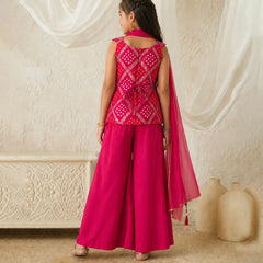 Woman in a pink traditional outfit standing in a room with white curtains and decorative elements.
