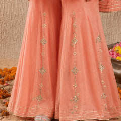 Peach-colored traditional outfit with intricate patterns on a sandy background