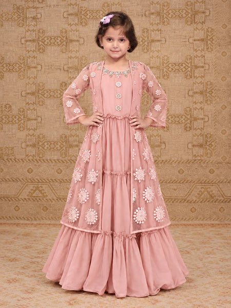 A pink traditional Indian dress with intricate floral embroidery and beadwork, shown on a model against a patterned beige background.