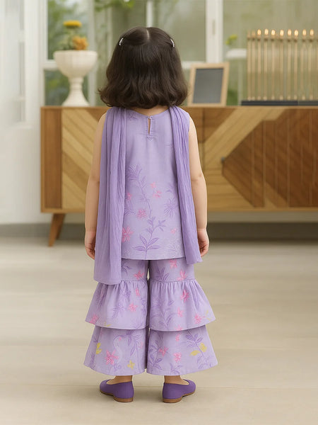 Child wearing a purple outfit with floral patterns in a room with wooden furniture.