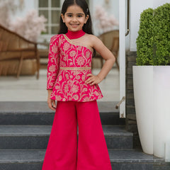 Young girl in a pink traditional outfit standing on steps outdoors.