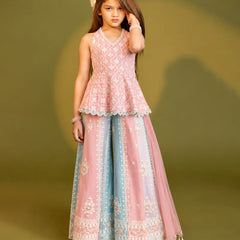 A young girl models a traditional Indian outfit consisting of a light pink sleeveless embroidered peplum top and matching wide-leg flared pants with a light blue and pink border, set against a solid olive green background.