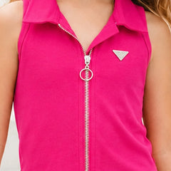 A close-up of a child wearing a bright pink sleeveless zip-up top with a collar, silver zipper, and a small triangular Guess logo on the chest.