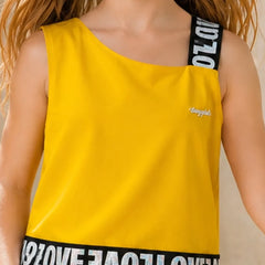 A child wearing a bright yellow one-shoulder tank top with black shoulder straps and a black hemband featuring white 'LOVE' lettering. The top has a small white script logo on the chest.