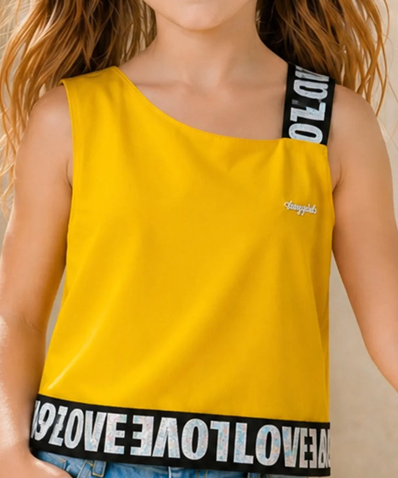 A child wearing a bright yellow one-shoulder tank top with black shoulder straps and a black hemband featuring white 'LOVE' lettering. The top has a small white script logo on the chest.