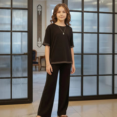 Woman wearing a black outfit standing in a room with large glass doors.