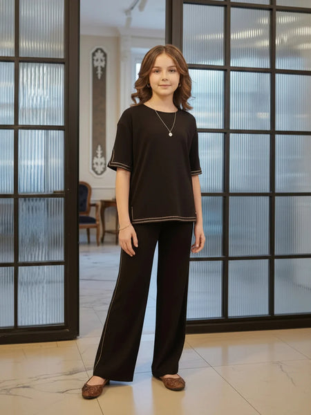 Woman wearing a black outfit standing in a room with large glass doors.