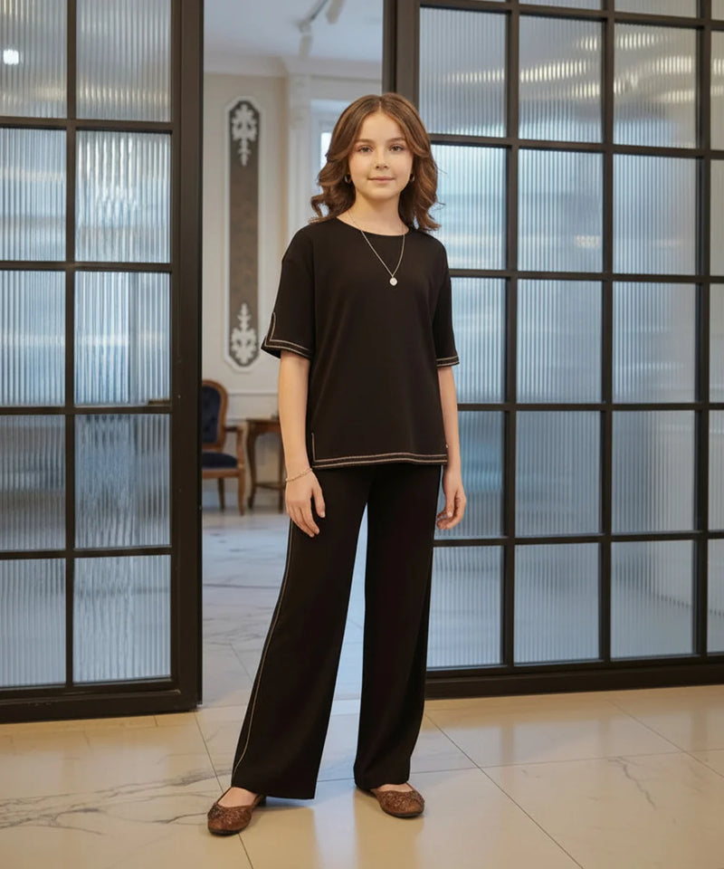 Woman wearing a black outfit standing in a room with large glass doors.