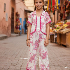 Young girl in a floral outfit standing on a street with market stalls in the background