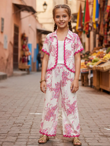Young girl in a floral outfit standing on a street with market stalls in the background