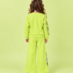 A child model shown from the back wearing a bright lime green two-piece tracksuit with a sweatshirt and wide-leg pants, featuring black graphic text on the sleeves and leg, set against a solid lime green background.