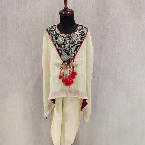 Traditional outfit with embroidered top and white pants on a mannequin against a plain background