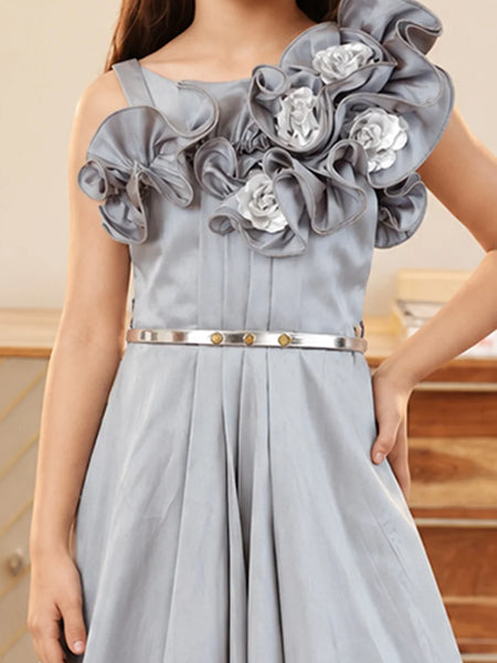 A light gray dress with a large ruffled floral bodice, a silver metallic belt with gold accents, and a pleated skirt, shown on a model.