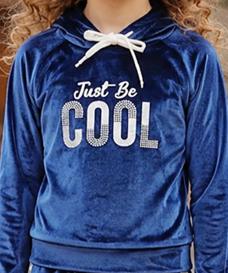 A close-up of a person wearing a royal blue velvet hoodie with a white drawstring and a rhinestone-style graphic that reads 'Just Be COOL' across the chest.