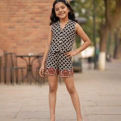 Young girl wearing a patterned dress standing on a sidewalk with a blurred background