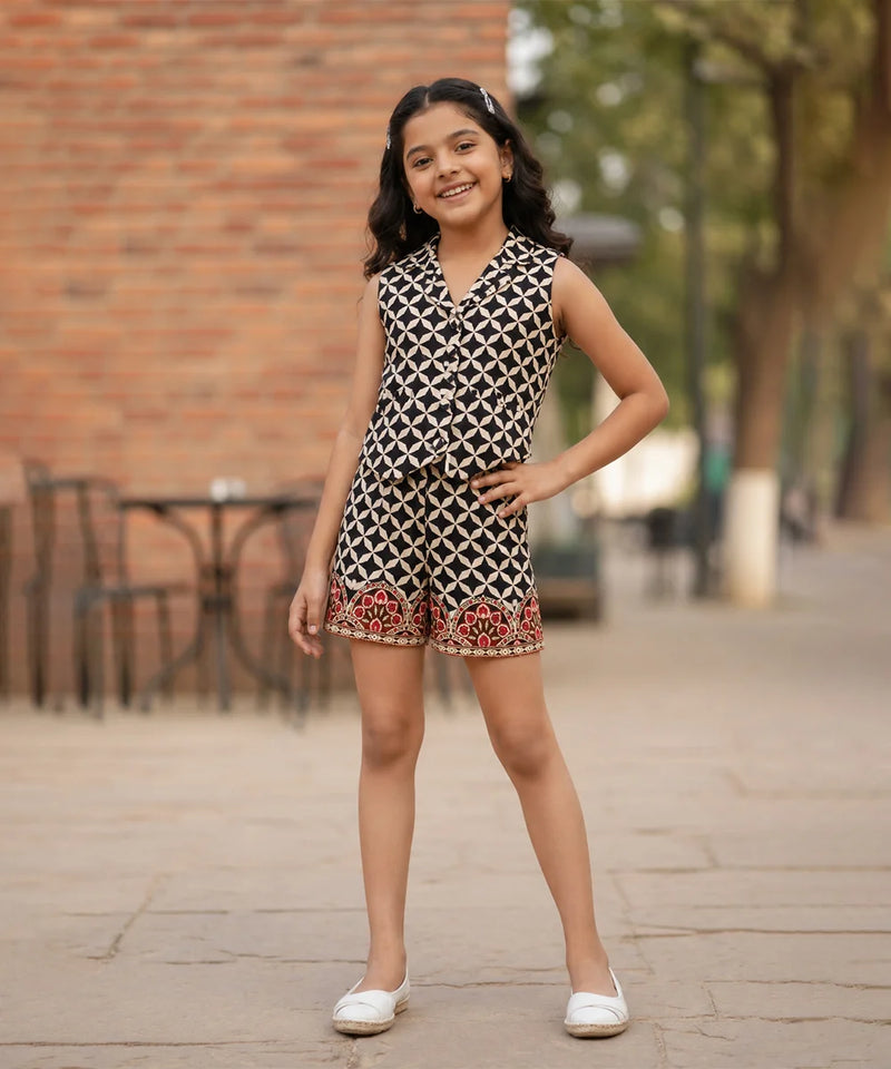 Young girl wearing a patterned dress standing on a sidewalk with a blurred background
