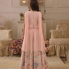 Woman wearing a pink floral dress in an elegant room with floral arrangements and furniture.