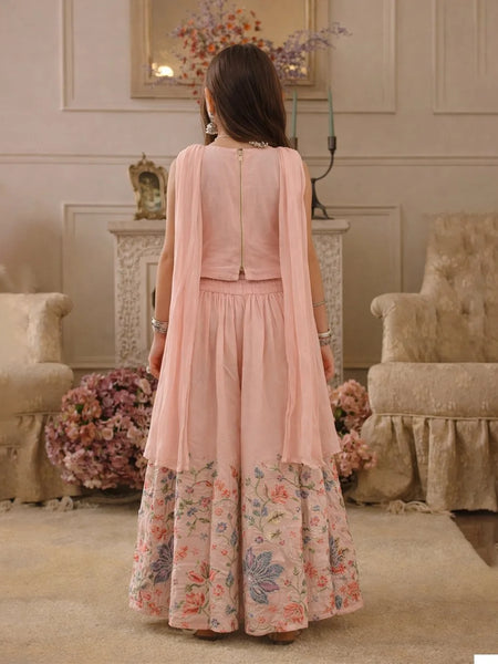 Woman wearing a pink floral dress in an elegant room with floral arrangements and furniture.