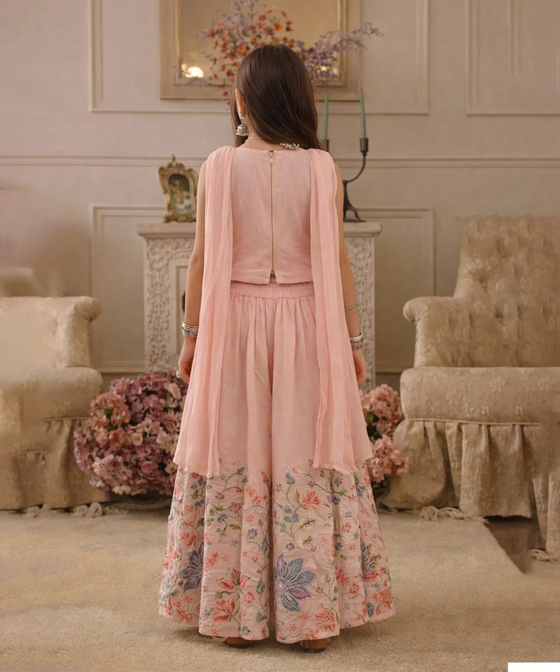 Woman wearing a pink floral dress in an elegant room with floral arrangements and furniture.