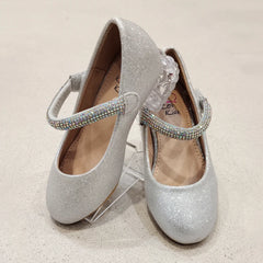 Pair of silver glitter shoes with rhinestone straps on a beige background
