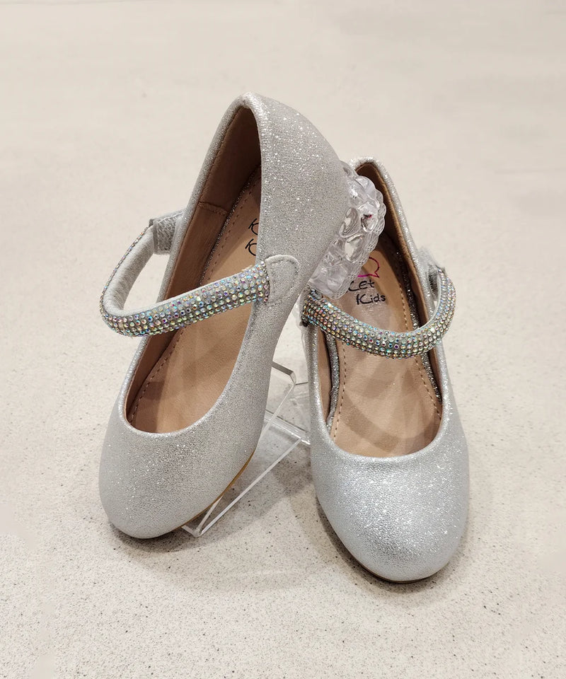 Pair of silver glitter shoes with rhinestone straps on a beige background