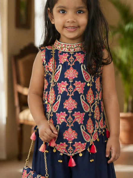 Young girl wearing a traditional embroidered top with pink floral patterns and red tassels.