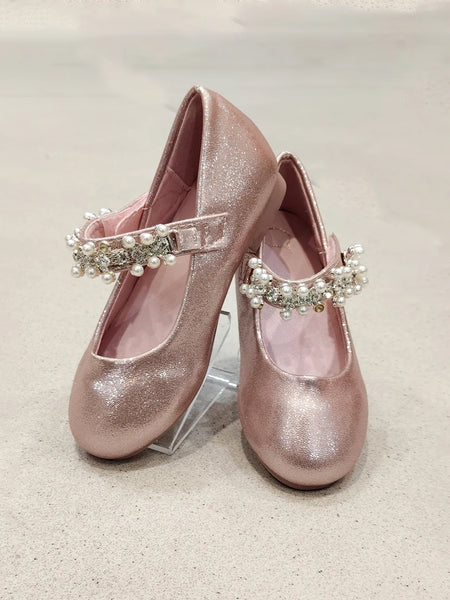 Pair of pink glittery shoes with pearl embellishments on a light background