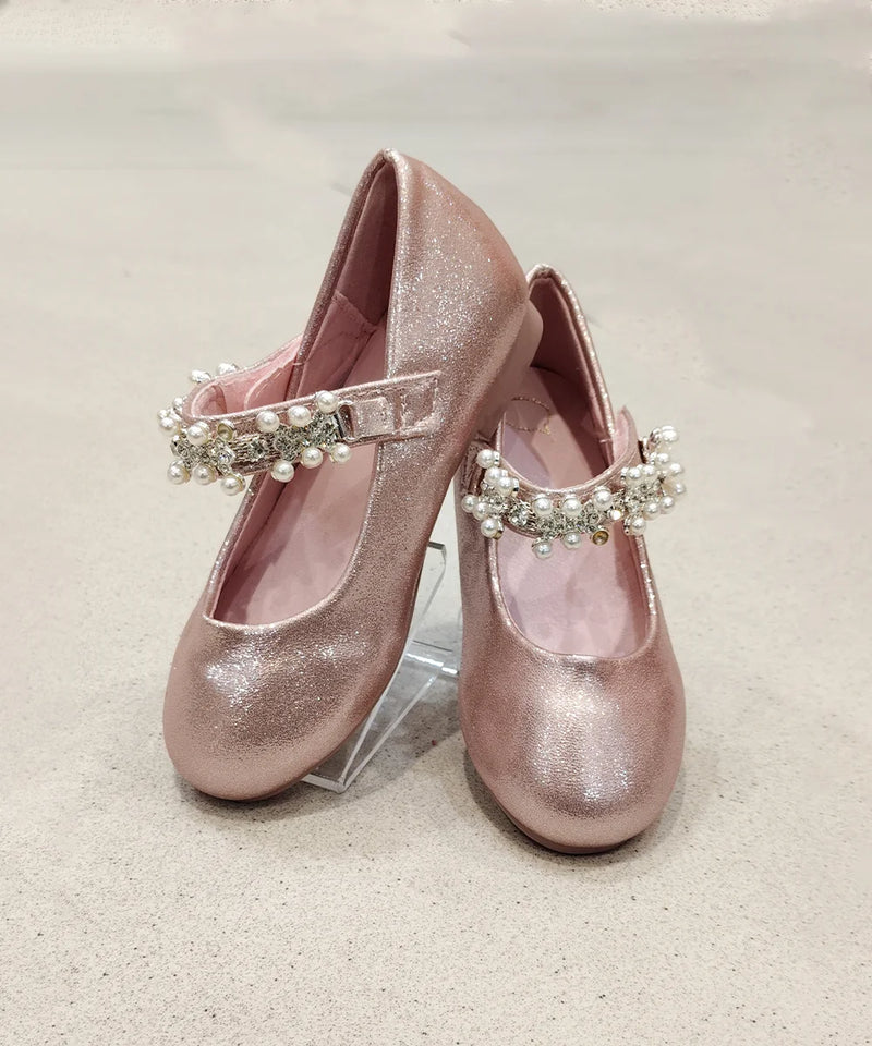 Pair of pink glittery shoes with pearl embellishments on a light background