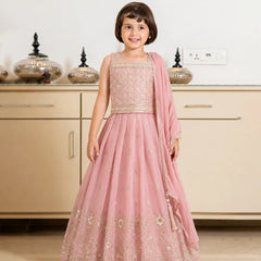 Young girl in a pink traditional outfit standing in a kitchen.