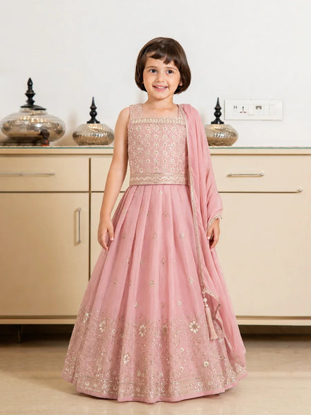 Young girl in a pink traditional outfit standing in a kitchen.
