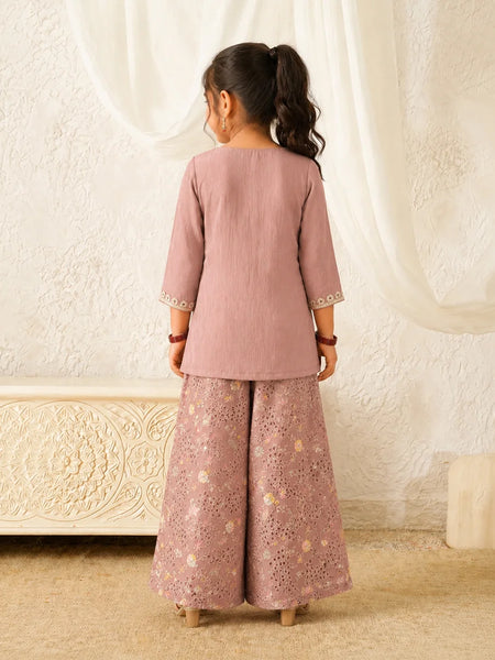 Person wearing a pink traditional outfit with a white textured wall background