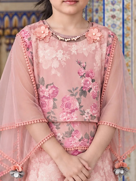 A pink floral embroidered tunic with sheer flutter sleeves, decorated with 3D flowers at the neckline and pom-pom trim, shown on a model in front of a patterned tile wall.