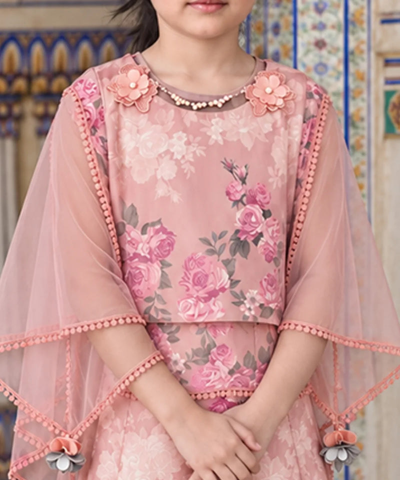 A pink floral embroidered tunic with sheer flutter sleeves, decorated with 3D flowers at the neckline and pom-pom trim, shown on a model in front of a patterned tile wall.