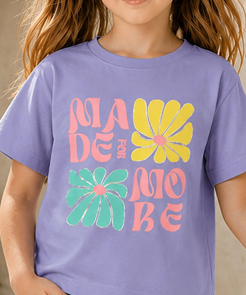 A child wearing a lavender purple t-shirt with a retro-style graphic that reads 'MADE FOR MOBE' in pink and yellow text, accented by two large yellow and green flowers on the front.